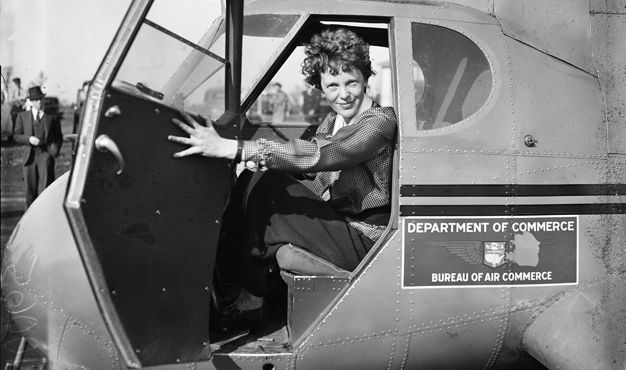 Aviator Amelia Earhart standing beside an aircraft